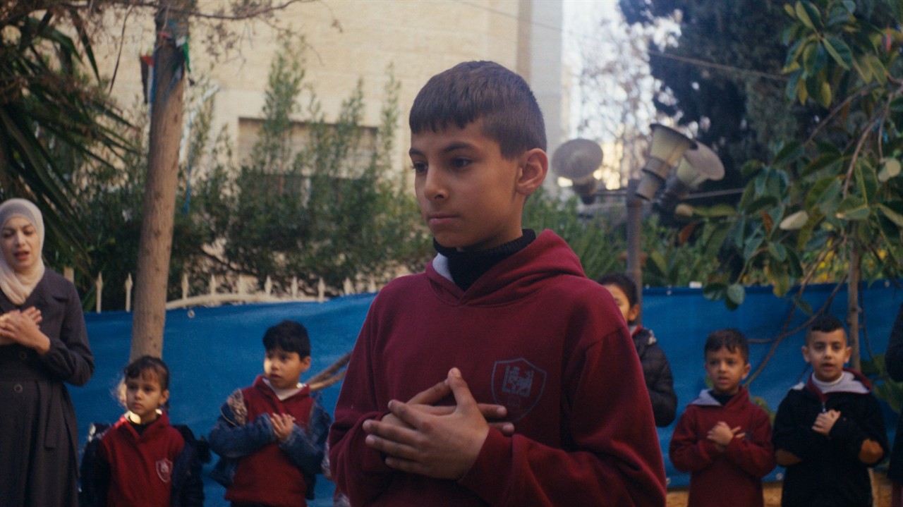A group of school children, hands clasped to chest